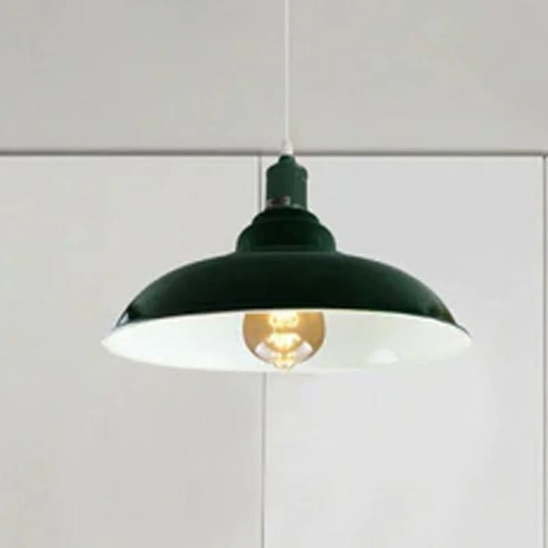 Green pendant ceiling light with metal dome shade, white interior, hanging from ceiling over a kitchen island.