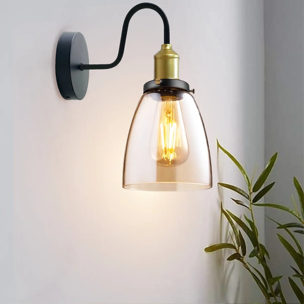 Modern amber glass wall light with copper‑plated base, hanging on wall, glowing amber shade.