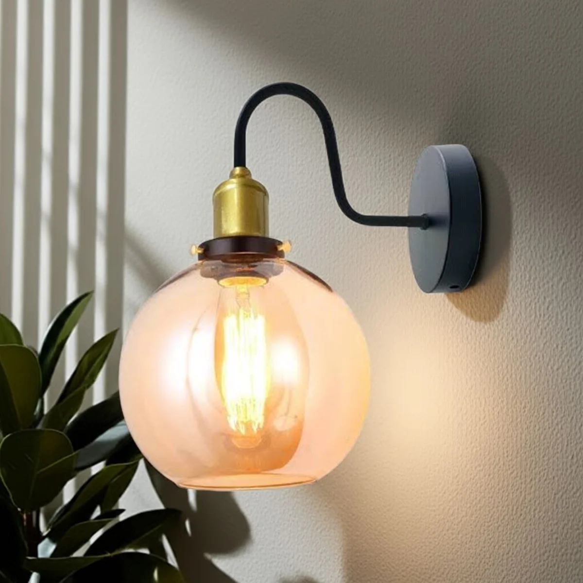 Modern wall sconce with amber glass globe shade and metal back plate.