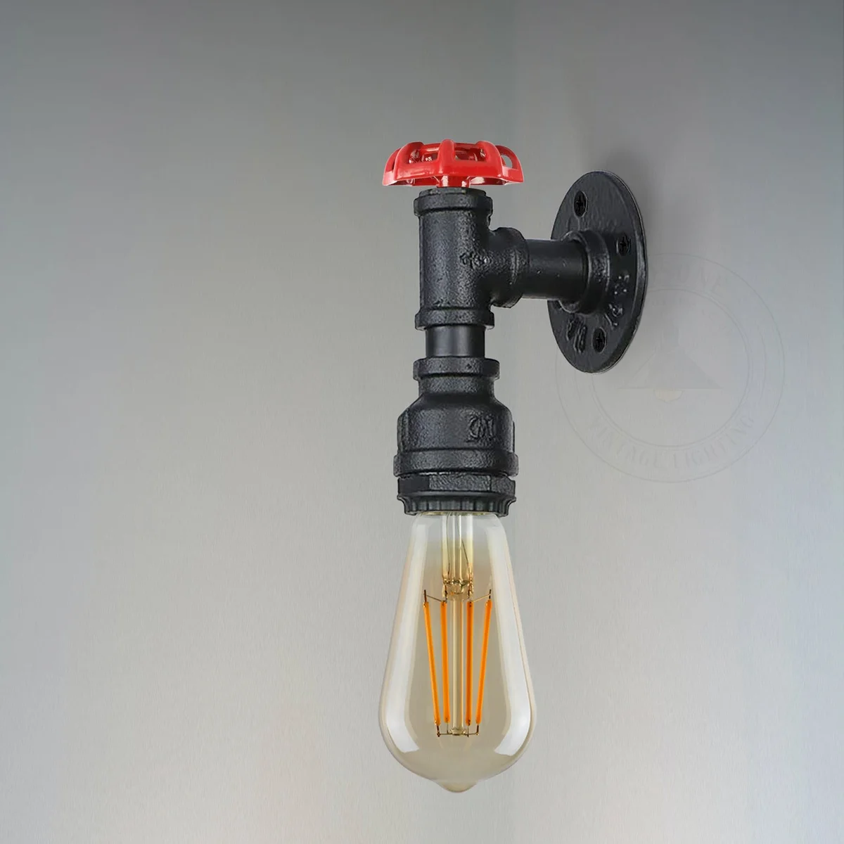 Vintage steampunk metal pipe wall light with red valve detail and E27 bulb socket mounted on a rustic wall