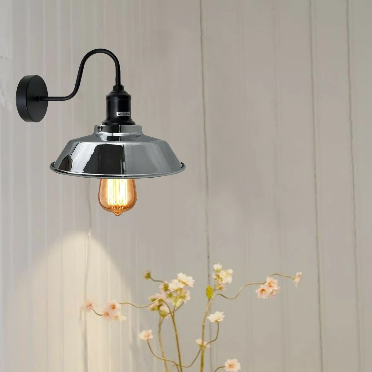 Chrome industrial wall lamp with swan neck arm and rustic vintage design mounted on white wall background