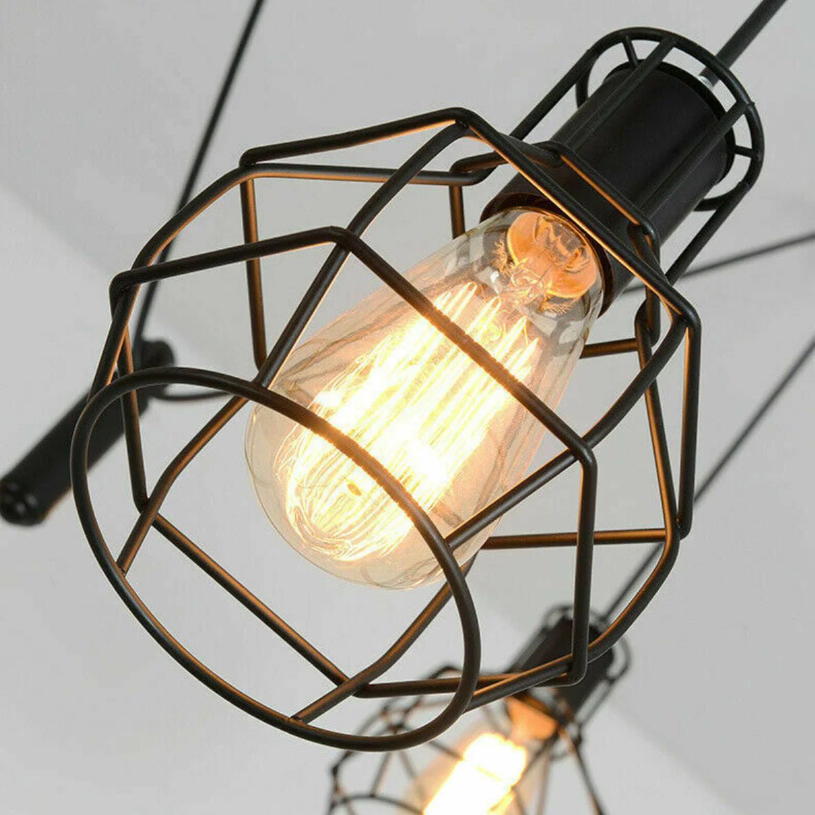 Adjustable spider pendant chandelier with six black metal wire cage lights and long adjustable cables hanging from ceiling