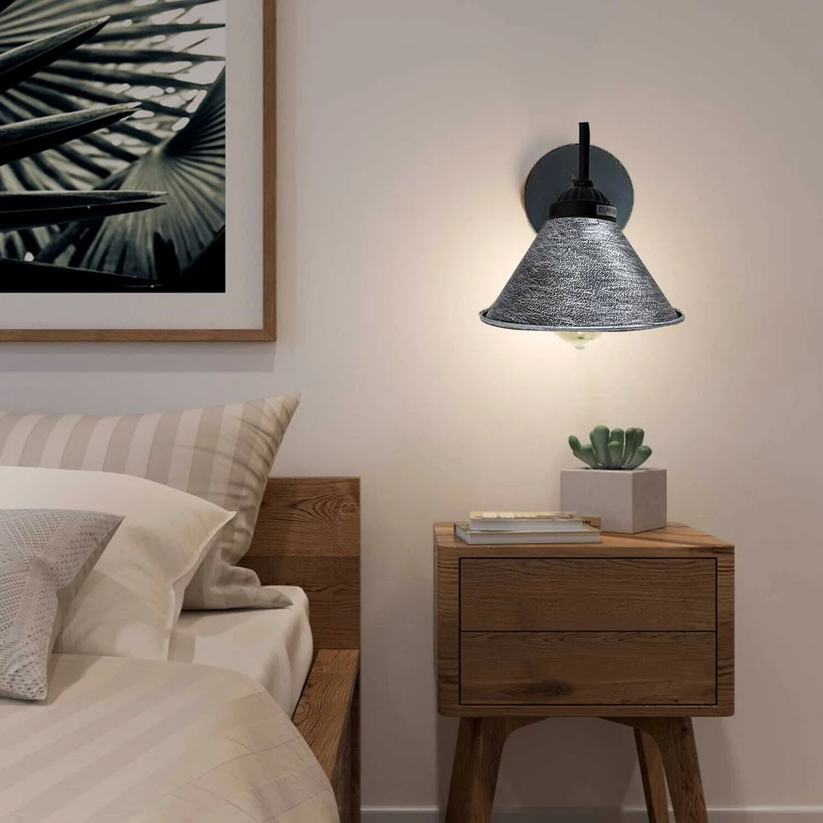 Brushed black silver lamp shade with black arm wall light mounted on white wall, showcasing rustic metal design