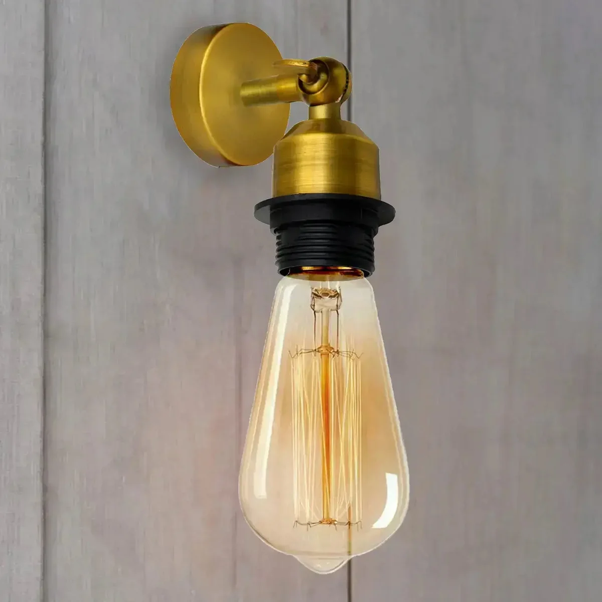 Industrial wall sconce in antique brass finish with adjustable pivot arm and E27 bulb fitting mounted on a wall