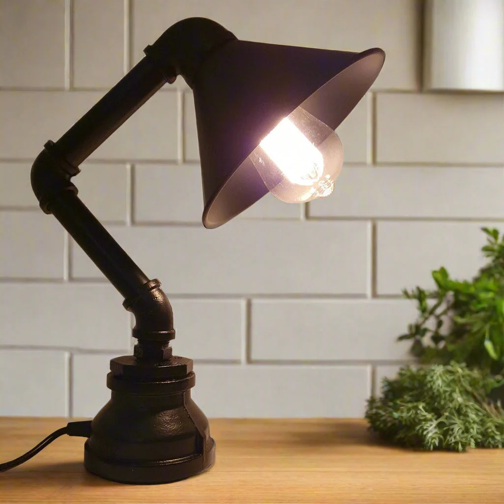 Vintage industrial pipe lamp with metal cone shade in black, showcasing steampunk water pipe design on wooden table