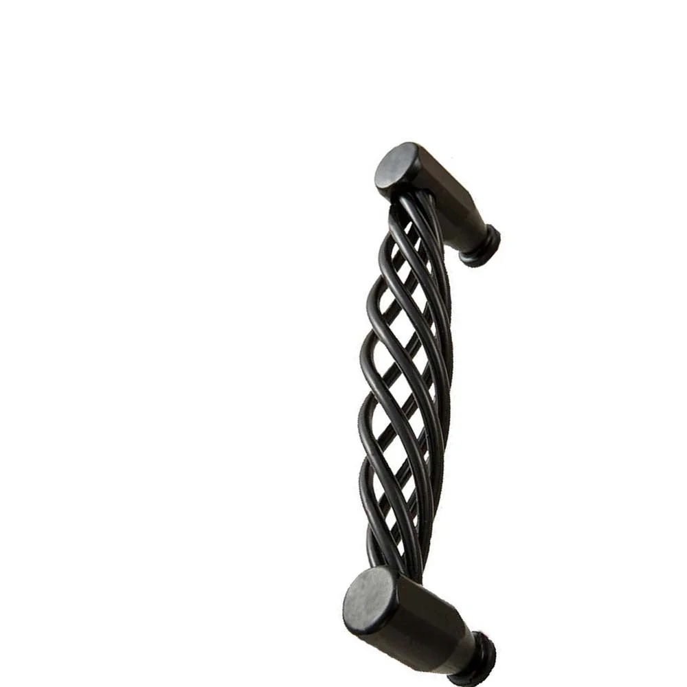 Close-up of a matt black cabinet handle mounted on a wooden drawer showing its vintage iron design and smooth grip.