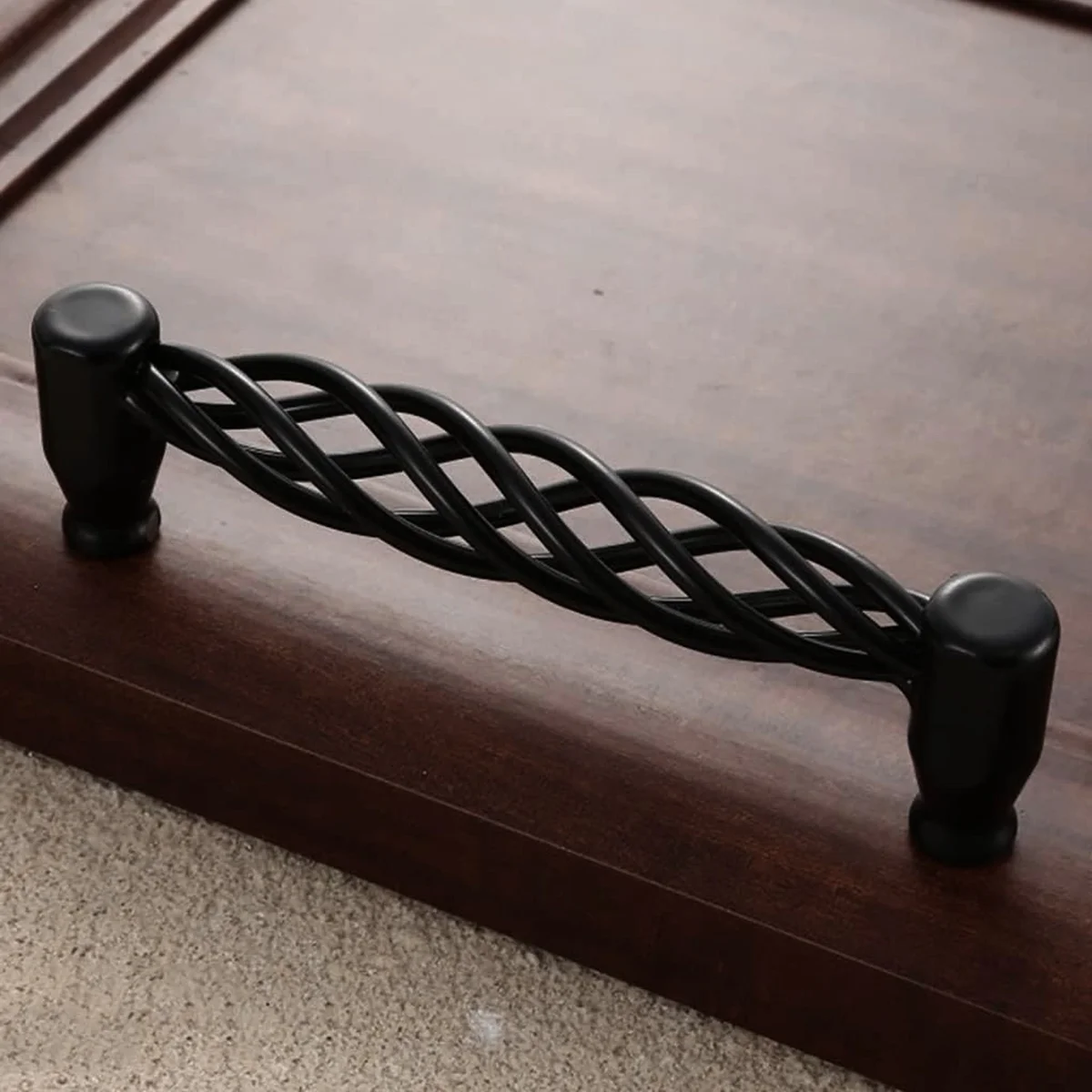 Close-up of matt black cabinet handles installed on wooden drawers with visible screw hardware and smooth finish
