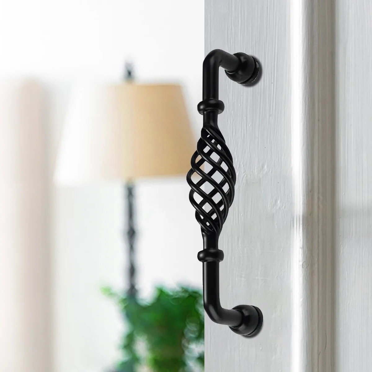 Vintage black birdcage metal kitchen cabinet handle 96mm, shown installed on wooden cupboard door