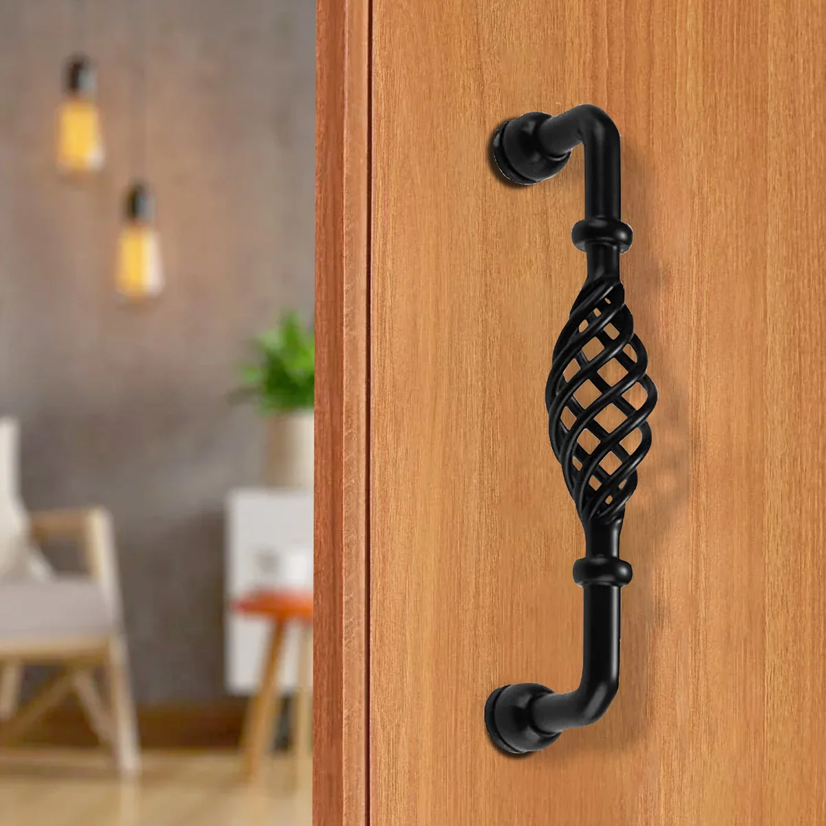 Vintage black birdcage cupboard pull handle in metal, shown mounted on wooden kitchen cabinet door