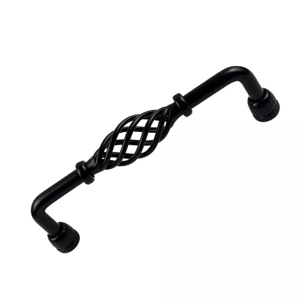 Vintage kitchen cabinet handle in black metal with birdcage design, mounted on a wooden cabinet door