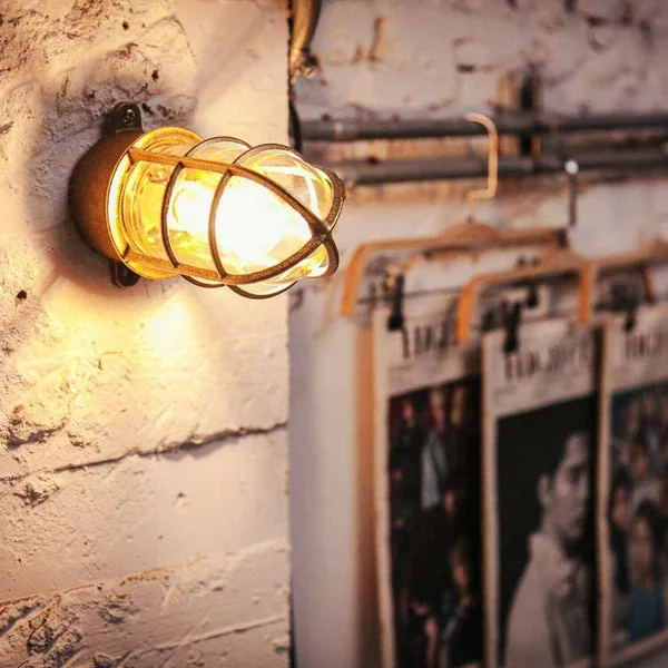 Vintage nautical bulkhead light with metal frame and glass lampshade, black finish, wall‑mounted design.
