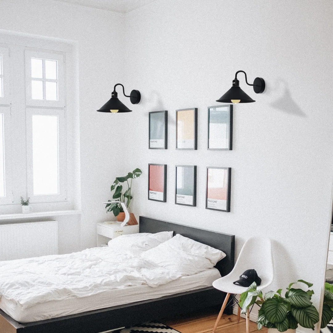 Black industrial swan neck wall light with vintage cone shade and curved arm mounted on a white wall