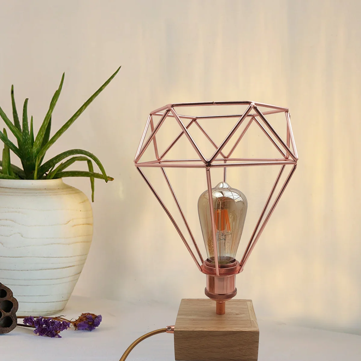Rose gold geometric wire cage modern desk light with dimmer switch on bedside table against white background