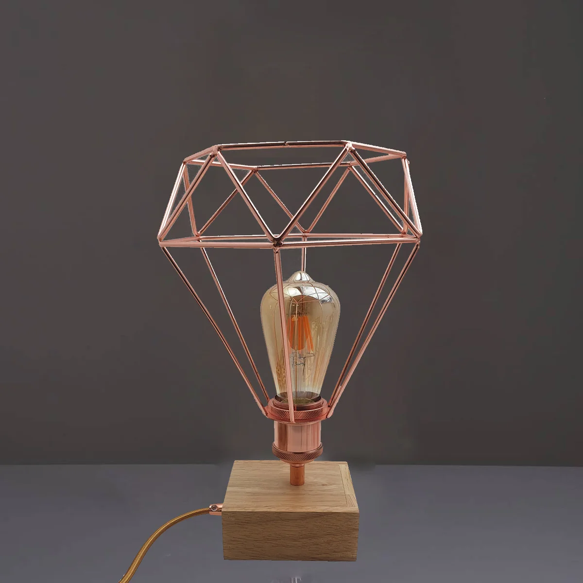 Vintage style lamp with rose gold geometric wire cage and slim base, ideal for bedside or desk lighting with dimmer switch