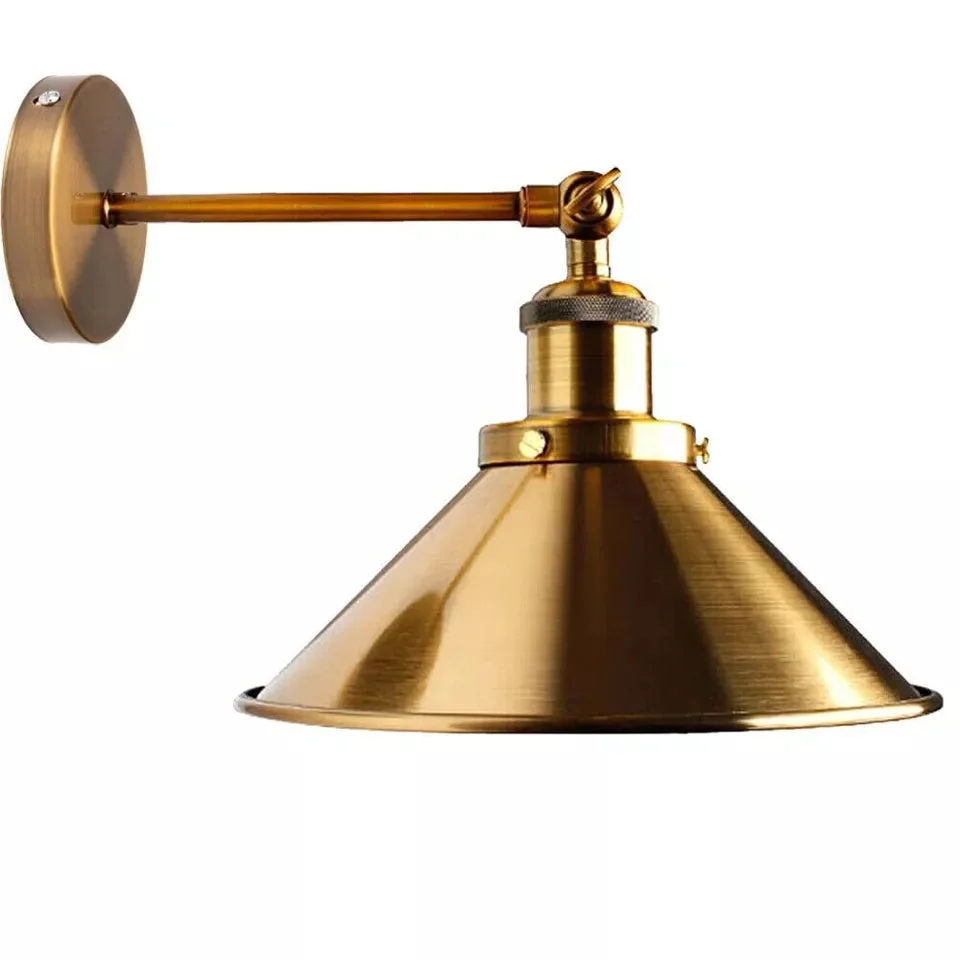 Adjustable industrial wall light with metal cone shade lamp in antique brass finish mounted on a white wall