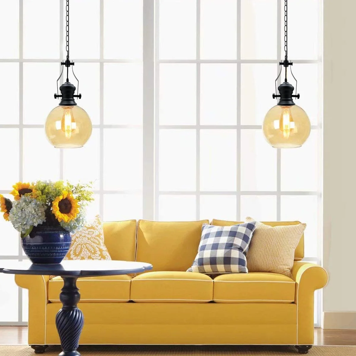 Amber glass industrial pendant light with black cage, suspended by 90cm chain and black PVC cable against white background