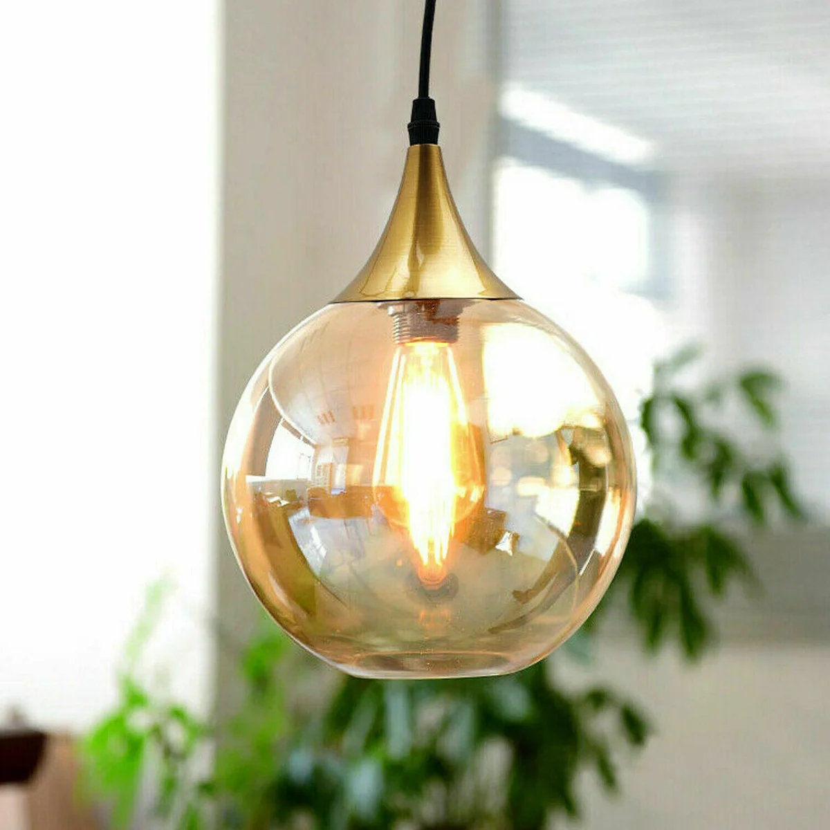 Amber glass pendant light with smoked blown glass shade and exposed iron hardware hanging from adjustable cord