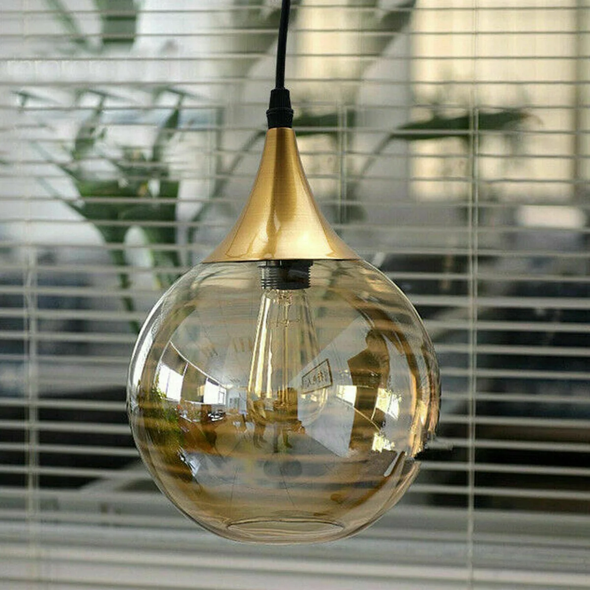 Smoked glass pendant light with amber globe and iron finish pendant light hardware hanging against white background