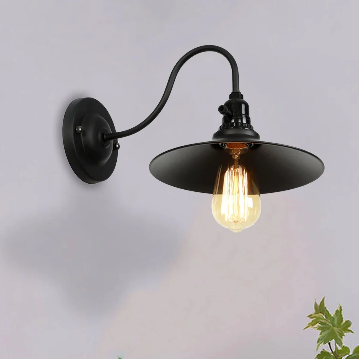 Iron industrial wall light cage with brass hold‑arm and ceiling rose, rustic style metal shade on wall.