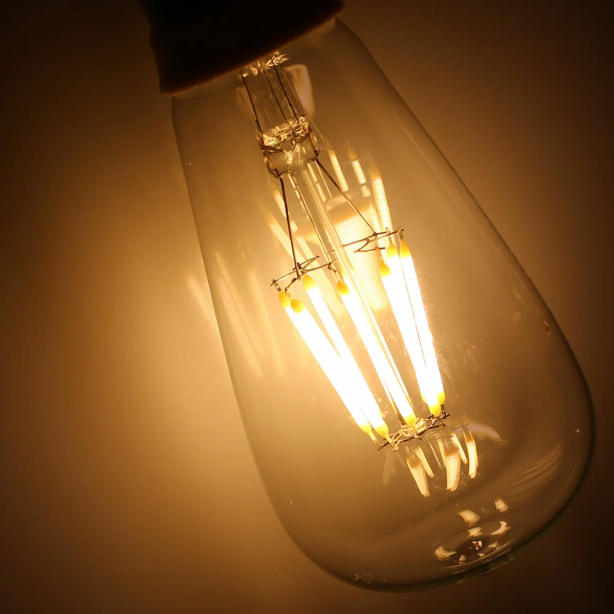 Vintage 8W E27 LED bulb with filaments, glowing warm white light, clear glass body, dimmable.