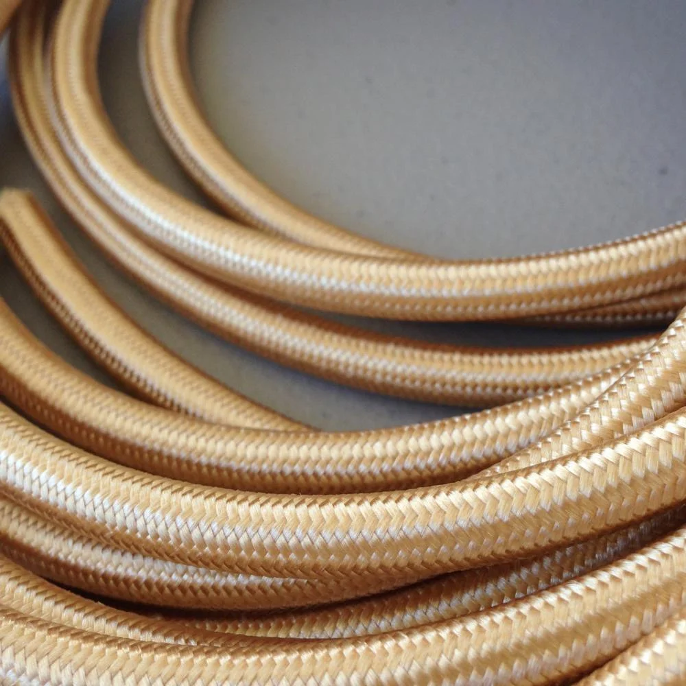 Gold colour cable, 2‑core braided fabric, 6 mm diameter, shown loosed on flat surface.