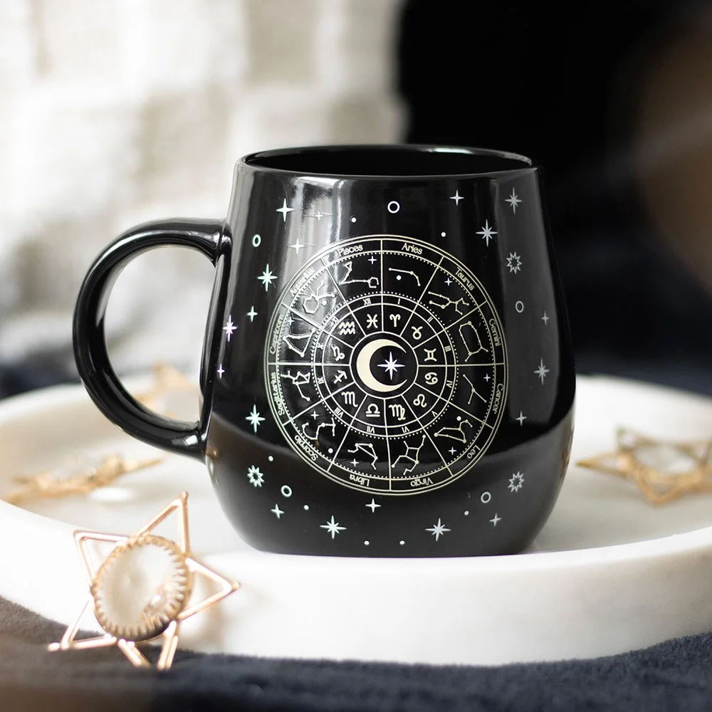 Black ceramic heat change mug with gold Astrology Wheel and stars design, 500ml capacity, dishwasher safe.