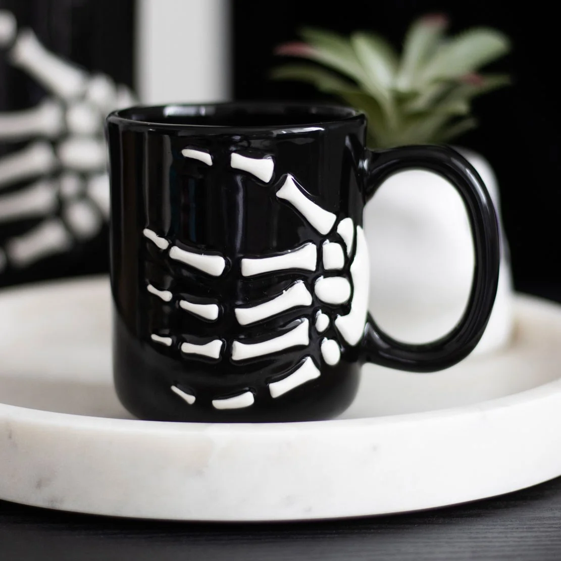 Skeleton hand mug with visible bones, ceramic cup holding coffee, 350ml capacity, handwash only.
