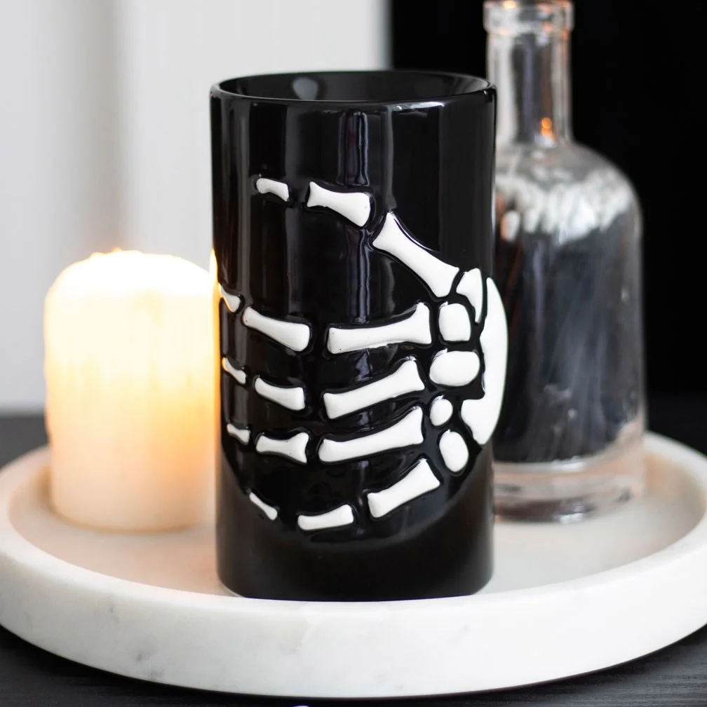 Skeleton hand oil burner with black base holding a small dish for warming fragrance oils in a spooky design
