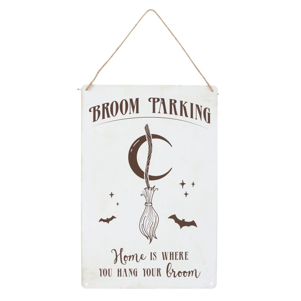 Metal broom parking sign with whimsical broom illustration and text "Home is where you hang your broom" on white background