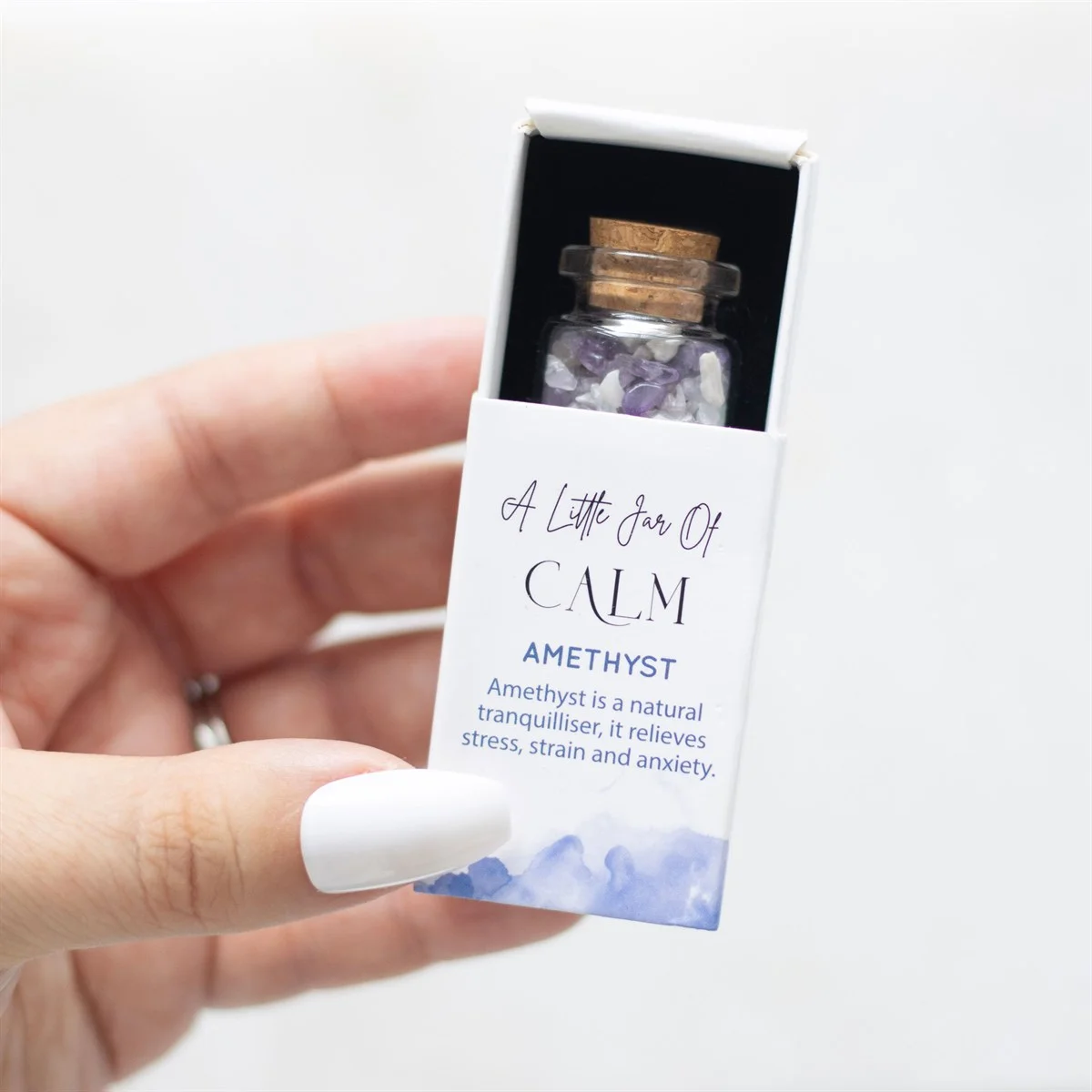 A compact matchbox holding an amethyst crystal jar filled with soothing violet chips.