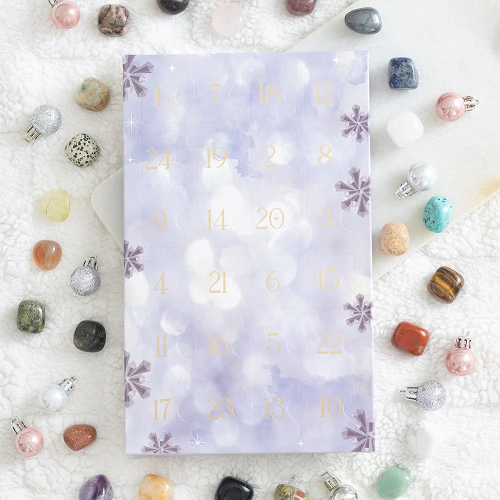Crystal advent calendar displaying 24 unique tumbled gemstones in numbered compartments for Christmas countdown.