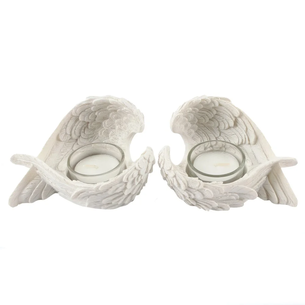 Pair of white resin winged candle holders shaped like angel wings holding tealight candles on a white background