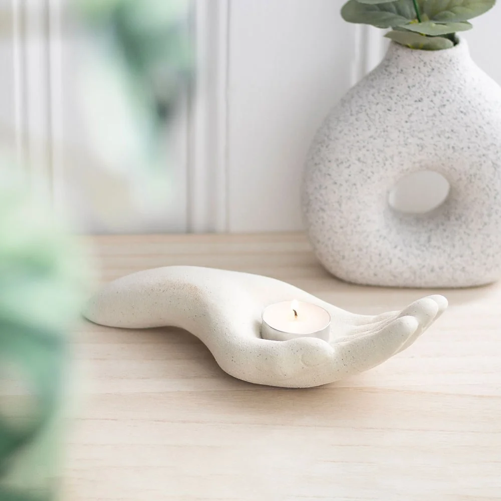 Open hand tealight holder shaped like a hand holding a lit tealight candle casting warm, soothing light