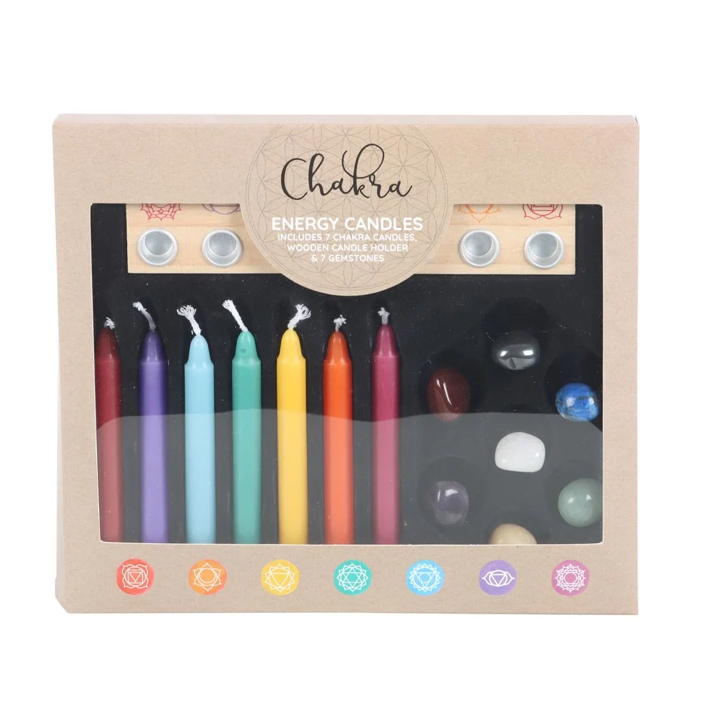 Chakra candle gift set with seven lit candles, wooden holder, and seven colorful chakra gemstones arranged neatly