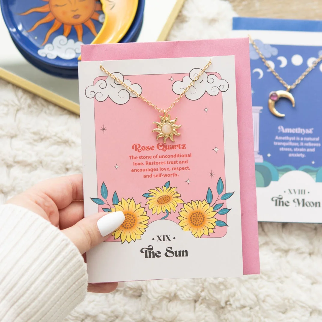 Sun pendant rose quartz necklace displayed on a colourful tarot-inspired greeting card with a pink envelope behind it