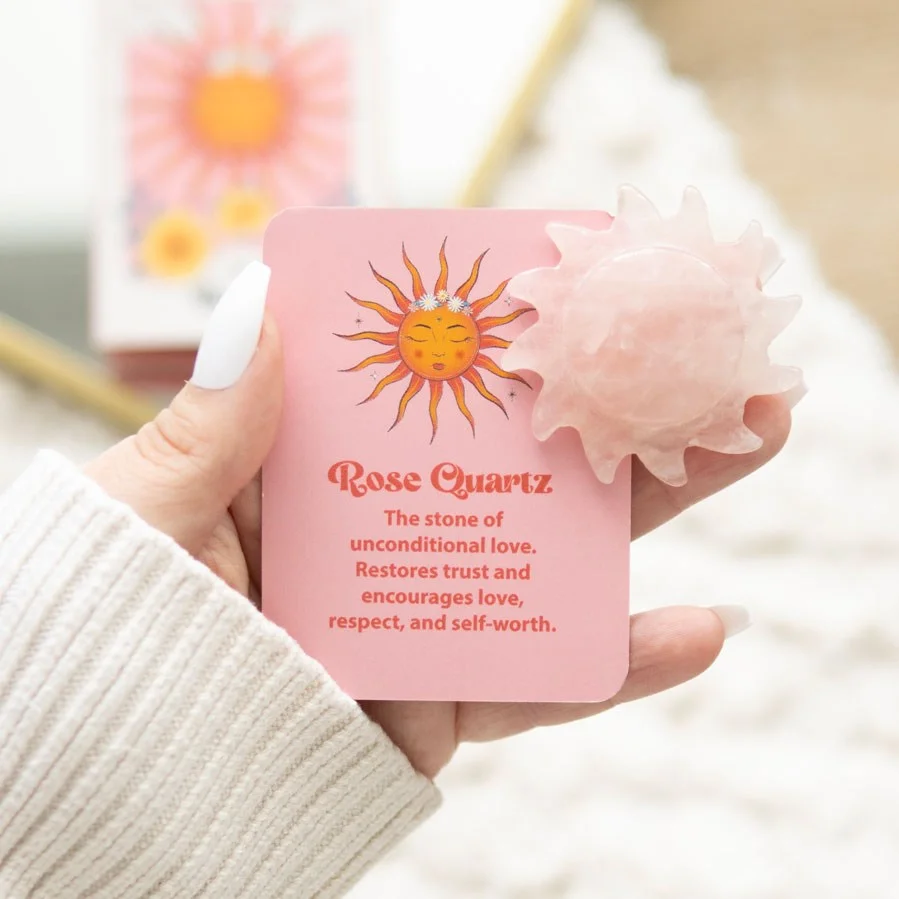 Rose quartz keepsake stone carved as a sun with pink hues, displayed in an open box on a white background