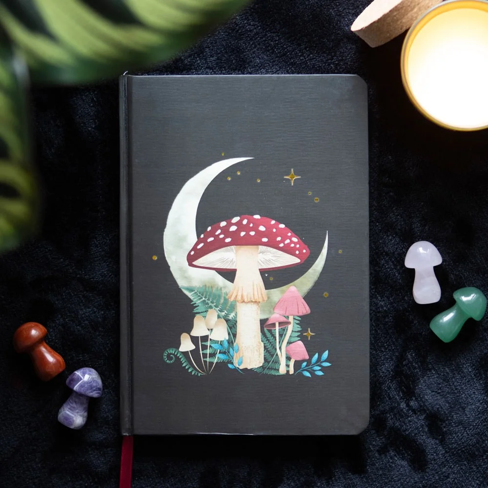 A5 notebook with mystical forest mushroom design, gold foil edges, and ribbon marker on white background