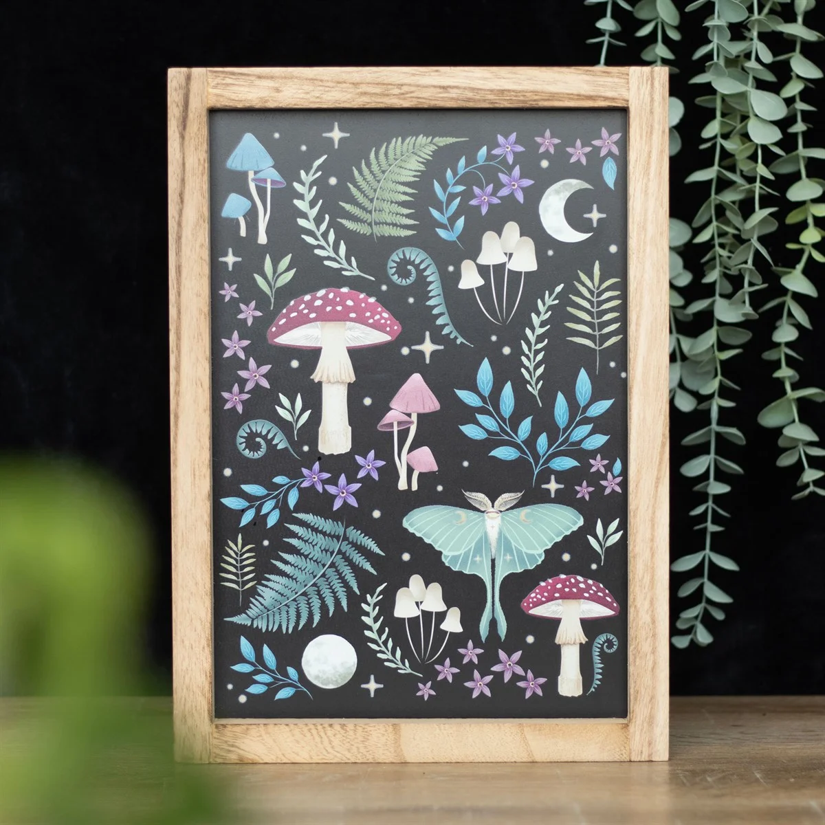 Dark forest wall print featuring mystical mushrooms, glowing luna moths, and magickal plants in a wooden frame