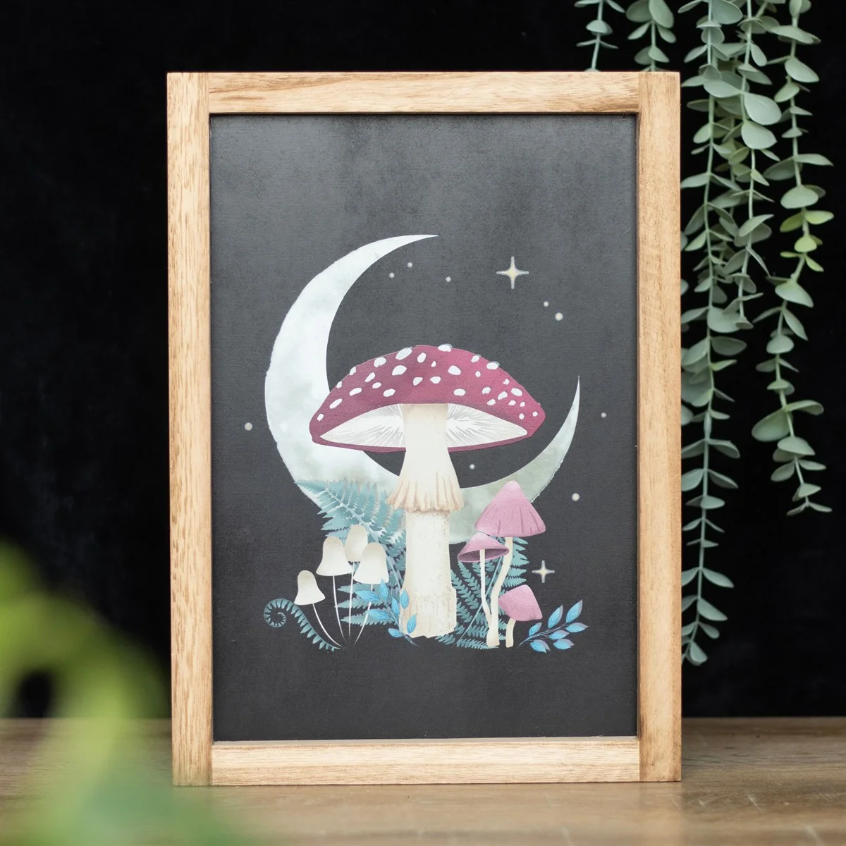 Framed forest mushroom wall print featuring mushrooms, crescent moon, and stars in a wooden frame on white background
