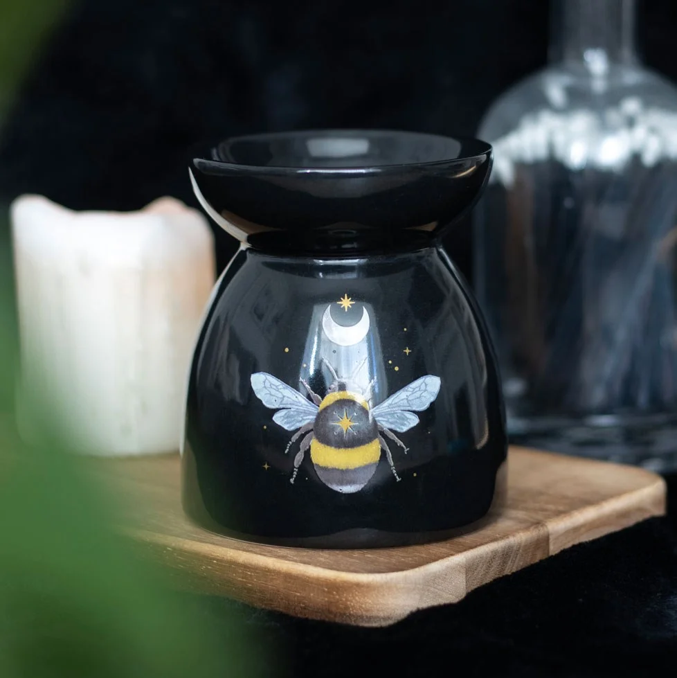 Black ceramic oil burner with forest bee design, holding a tealight under moon and stars motif