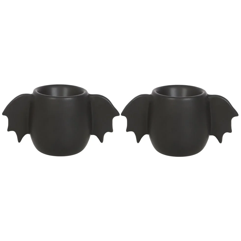 Pair of black bat wing egg cups holding boiled eggs on a white background for breakfast use