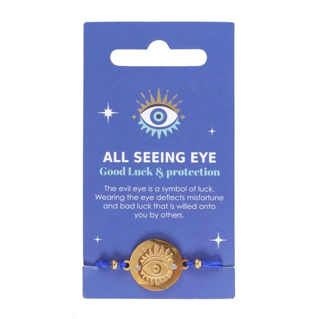 Gold-toned all seeing eye bracelet on blue string displayed on a blue card with charm meaning text visible