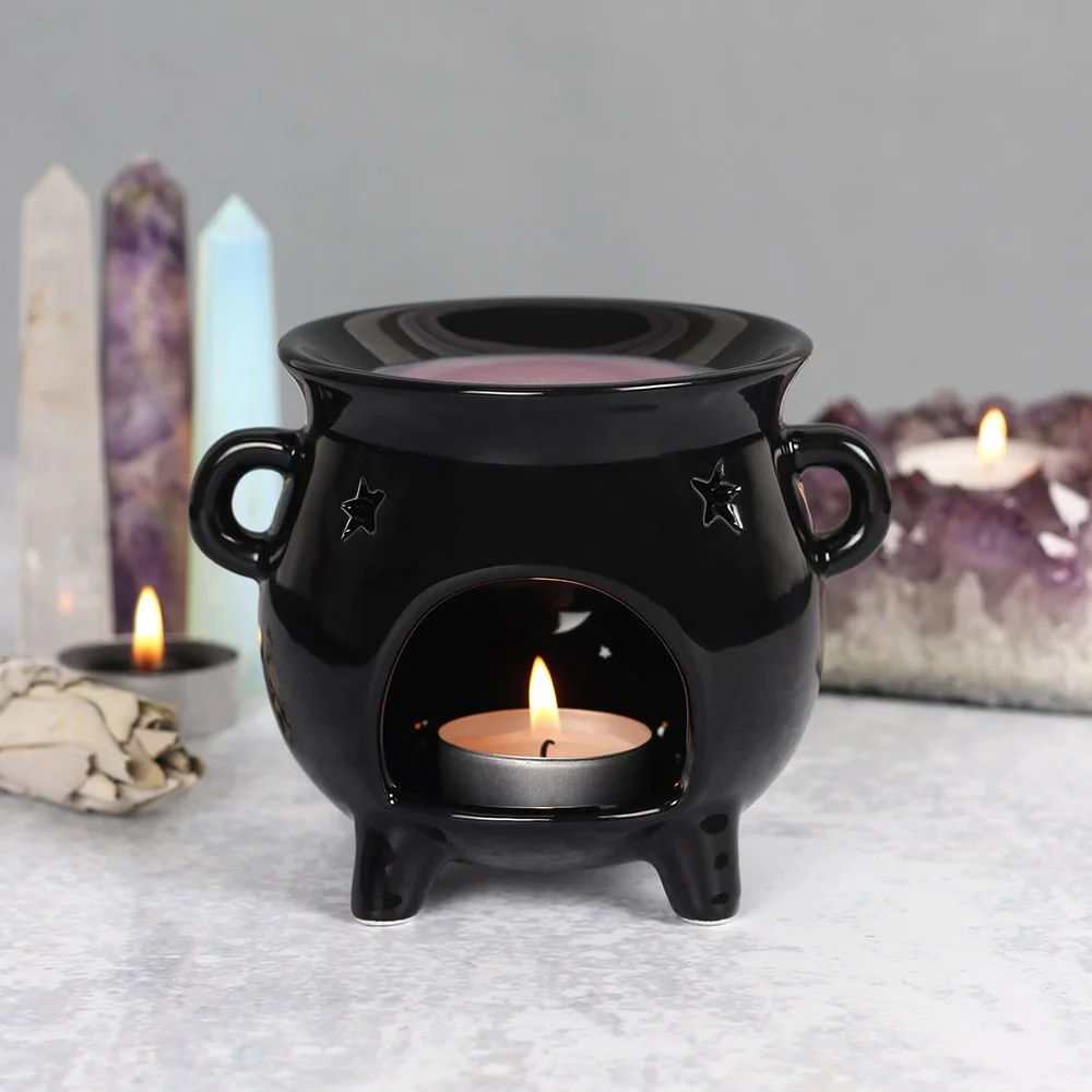Black cauldron oil burner with star cut-out design, used for fragrance oils or wax melts, 10cm tall.