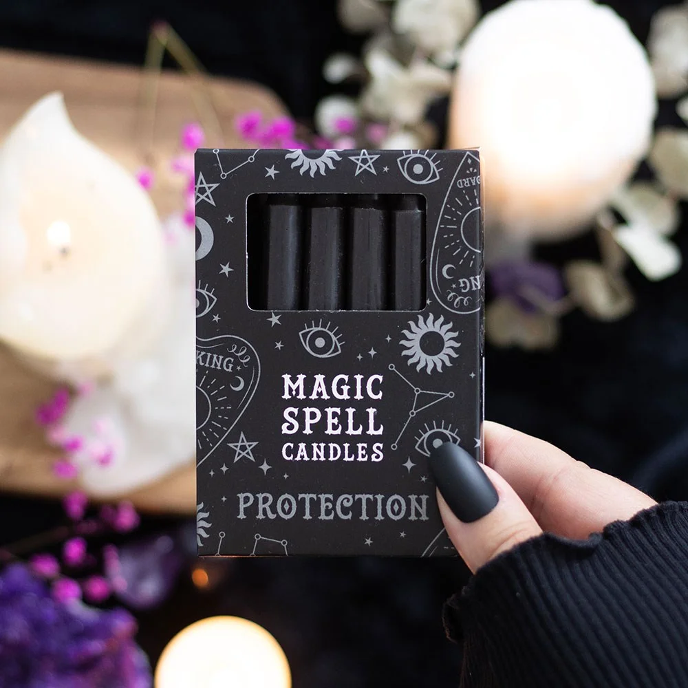 12 black protection candles neatly arranged in a pattern, their dark wax glowing.