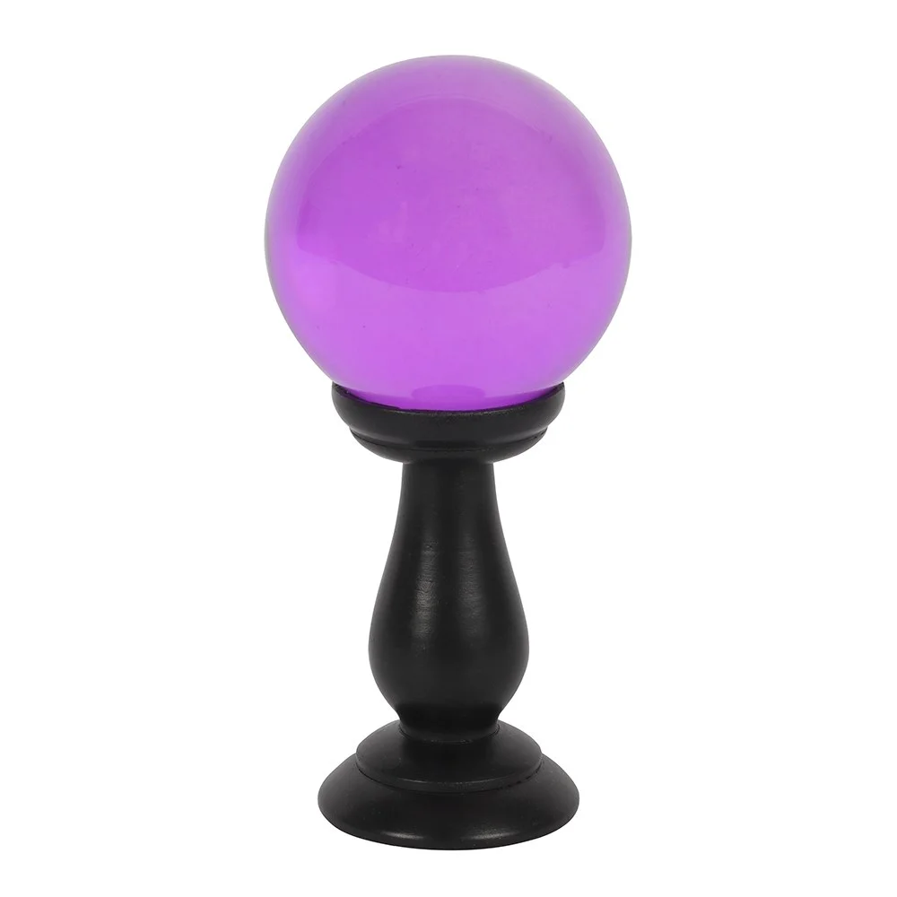 Small purple crystal ball on a black wooden stand, resting on a flat surface with light highlighting its polished surface.