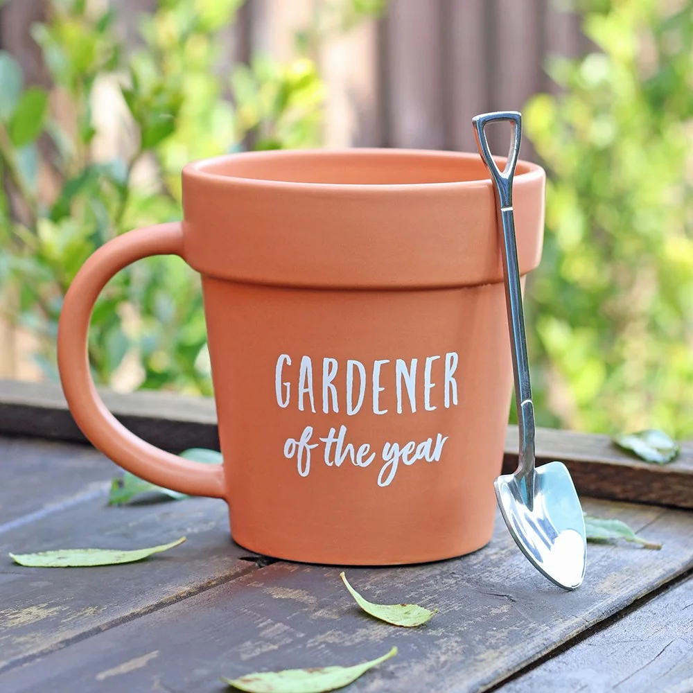 Terracotta gardener mug shaped like a plant pot with matching shovel spoon on a white background