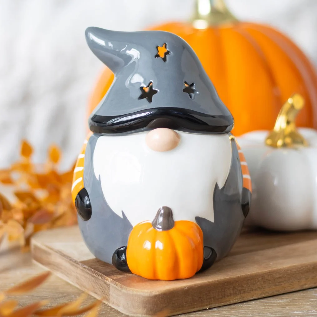 Grey and orange Halloween oil burner shaped like a gonk with pumpkin detail and star cut-out hat casting warm light