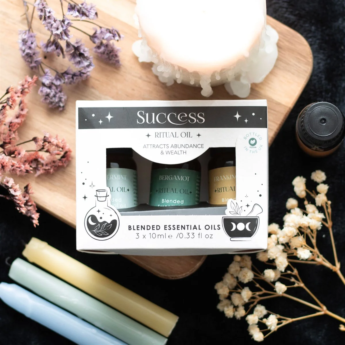 Set of 3 success ritual essential oils bottles with labels for Frankincense, Bergamot, and Peppermint on white background
