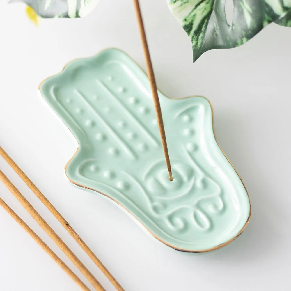 Blue ceramic hamsa hand incense holder shaped like the hand of Fatima with a slot for incense sticks and ash catcher