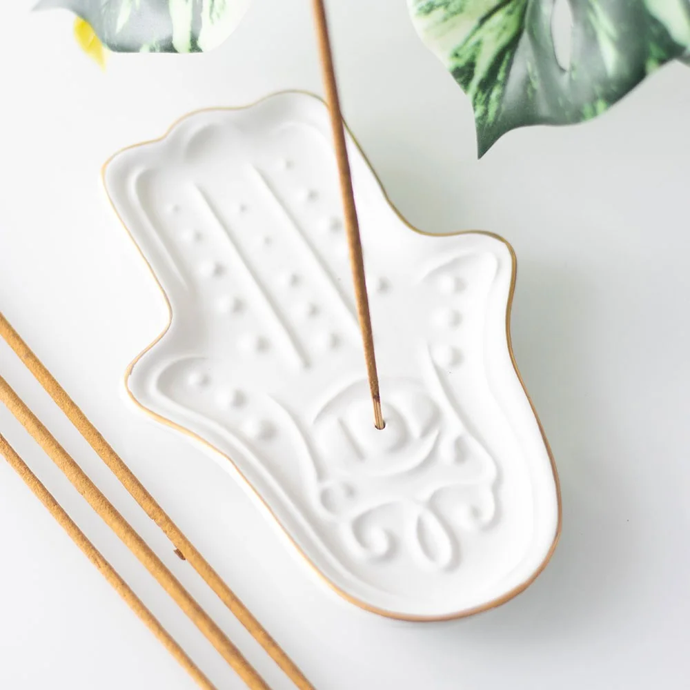 White ceramic hamsa hand incense holder shaped like the hand of Fatima with a slot for incense sticks